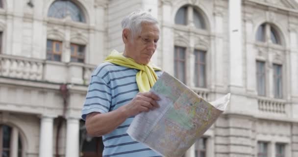Старший турист, исследующий город с картой в руках и ищущий маршрут — стоковое видео