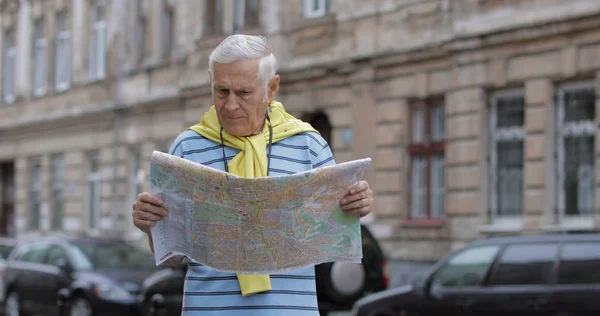Senior férfi turisztikai feltárása város egy térképet a kezében, és keresi az útvonalat — Stock Fotó