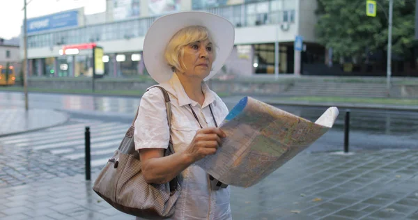 Senior női turizmus feltárása város egy térképet a kezében. Keresi az útvonalat — Stock Fotó