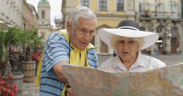 Senior mannelijke en vrouwelijke toeristen staan met een kaart in handen op zoek naar route — Stockfoto