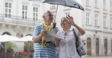 Mutlu üst düzey turistler şehir merkezinde durmak ve Lviv yağmurlu havanın tadını çıkarın