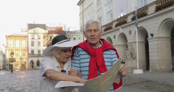Senior mannelijke en vrouwelijke toeristen wandelen met een kaart in handen op zoek naar route — Stockvideo