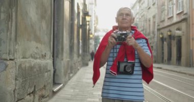 Üst düzey erkek turist şehir keşfetmek ve fotoğraf makinesi ile bir fotoğraf yapar