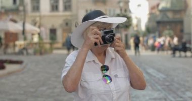Büyük kadın turist şehir keşfetmek ve retro fotoğraf makinesi ile bir fotoğraf yapar
