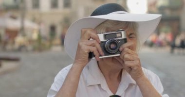 Büyük kadın turist şehir keşfetmek ve retro fotoğraf makinesi ile bir fotoğraf yapar