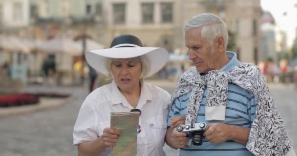 Senior manliga och kvinnliga turister stående med en karta i händerna söker rutt — Stockvideo