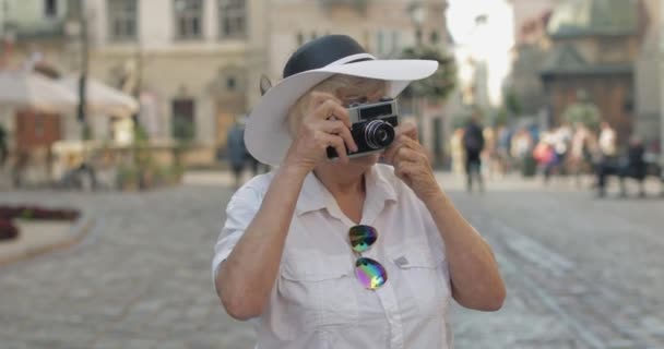 Senior vrouwelijke toerist verkennen van de stad en maakt een foto met retro fotocamera — Stockvideo