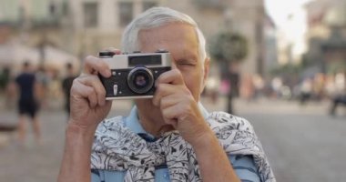 Kıdemli erkek turist şehir keşfetmek ve retro fotoğraf makinesi ile bir fotoğraf yapar