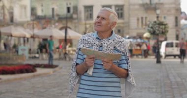 Üst düzey erkek turist elinde bir harita ile şehir keşfetmek. Rotayı arıyorum