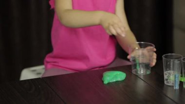 Çocuk elleri yeşil balçıkla eğleniyor. El yapımı oyuncak balçıkile oynayan çocuk