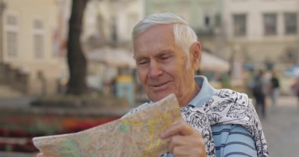 Senior turista masculino explorando la ciudad con un mapa en las manos. Buscando la ruta — Vídeos de Stock