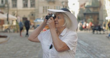 Büyük kadın turist şehir keşfetmek ve retro fotoğraf makinesi ile bir fotoğraf yapar