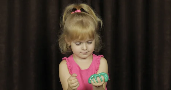 Дитина розважається, роблячи зелений слиз. Дитина грає з ручним іграшковим слизом — стокове фото