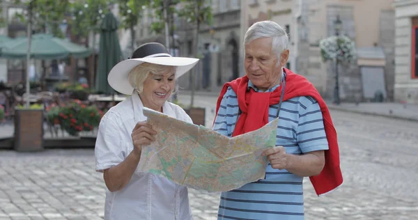 Senior mannelijke en vrouwelijke toeristen staan met een kaart in handen op zoek naar route — Stockfoto