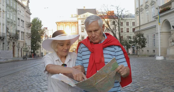 Senior mannelijke en vrouwelijke toeristen wandelen met een kaart in handen op zoek naar route — Stockfoto
