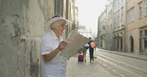 Turista sênior explorando a cidade com um mapa nas mãos. Olhando para a rota — Fotografia de Stock