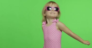 Pembe mayo giyen çocuk spor yapıyor, kız spor yapıyor ve dans ediyor.
