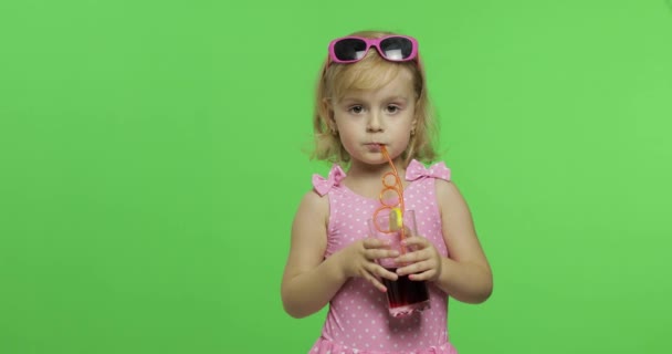 ピンクの水着を着た子供はストローを飲みながらジュースカクテルを飲みます。クロマキー — ストック動画