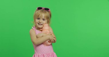 Pembe mayogiyen çocuk oyuncak bir domuzla oynuyor. Renk Anahtarı