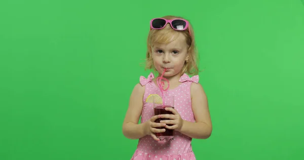 Bambino in costume da bagno rosa beve succo di cocktail con paglia da bere. Chiave cromatica — Foto Stock