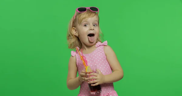 Niño en traje de baño rosa mostrar la lengua y tiene jugo cóctel con paja para beber —  Fotos de Stock