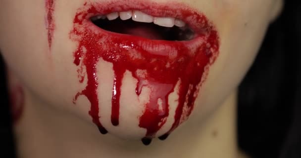 Blutiger Mund und Zähne des Mädchens. Vampir-Halloween-Make-up mit tropfendem Blut