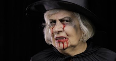 Yaşlı cadı Cadılar Bayramı makyajı. Yüzünde kan olan yaşlı kadın portresi.