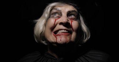 Yaşlı cadı Cadılar Bayramı makyajı. Yüzünde kan olan yaşlı kadın portresi.