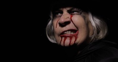 Yaşlı cadı Cadılar Bayramı makyajı. Yüzünde kan olan yaşlı kadın portresi.