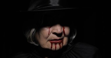 Yaşlı cadı Cadılar Bayramı makyajı. Yüzünde kan olan yaşlı kadın portresi.