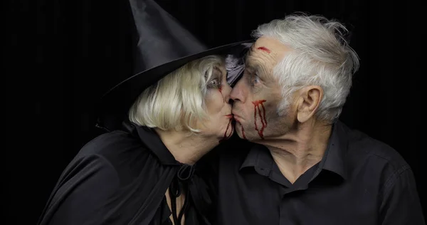 Ältere Männer und Frauen in Halloween-Kostümen, die sich küssen. Hexe und Zombie — Stockfoto