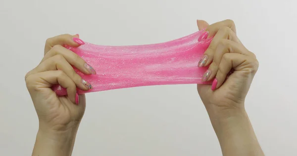 Woman hands playing oddly satisfying pink slime on white background. Antistress