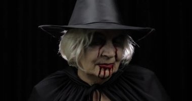 Yaşlı cadı Cadılar Bayramı makyajı. Yüzünde kan olan yaşlı kadın portresi.