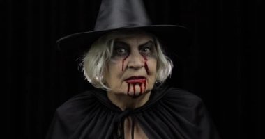 Yaşlı cadı Cadılar Bayramı makyajı. Yüzünde kan olan yaşlı kadın portresi.