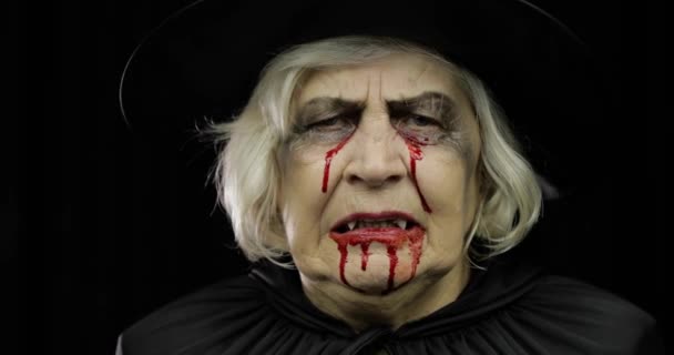 Old witch Halloween makeup. Elderly woman portrait with blood on her face. — Stock Video