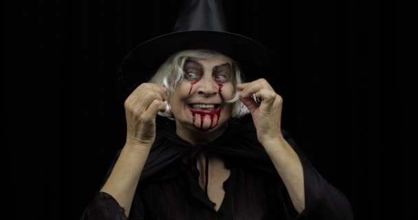 Old witch Halloween makeup. Elderly woman portrait with blood on her face. — Stock Video