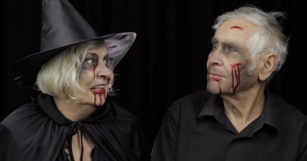 Elderly man and woman in Halloween costumes making a kiss. Witch and zombie — Stock Video