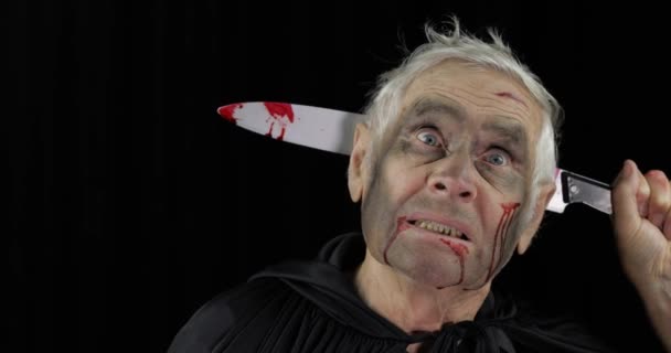Пожилой человек с ножом в голове. Хэллоуин макияж и костюм. Кровь на лице — стоковое видео