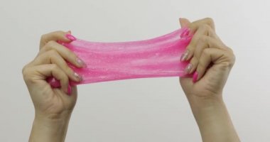 Kadın elleri beyaz arka plan üzerinde garip tatmin edici pembe balçık oynuyor. Antistres