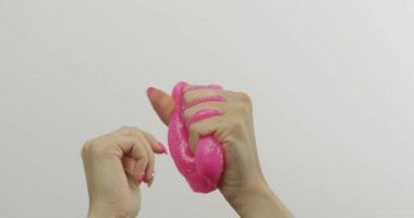 Kadın elleri beyaz arka plan üzerinde garip tatmin edici pembe balçık oynuyor. Antistres