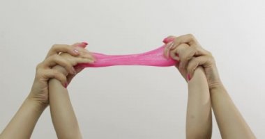 Kadın ve çocuk elleri beyaz arka planda garip pembe balçık oynuyor. Antistres