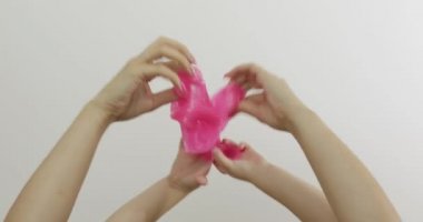 Kadın ve çocuk elleri beyaz arka planda garip pembe balçık oynuyor. Antistres