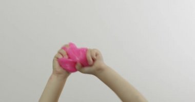 Çocuk elleri beyaz arka plan üzerinde garip tatmin edici pembe balçık oynuyor. Antistres
