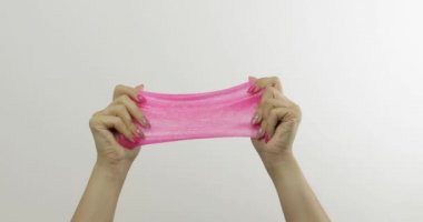 Kadın elleri beyaz arka plan üzerinde garip tatmin edici pembe balçık oynuyor. Antistres