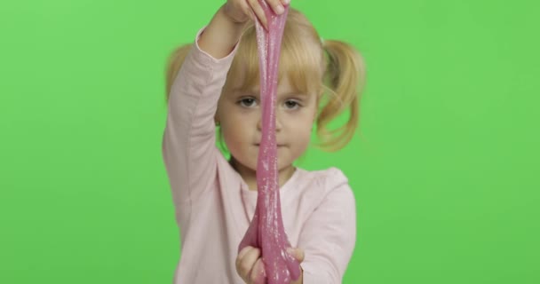 Малюк грає з ручним іграшковим слизом. Дитина весело робить рожевий слиз — стокове відео
