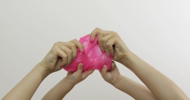 Manos de mujer y niño jugando baba extrañamente rosa sobre fondo blanco. Antiestrés — Vídeos de Stock