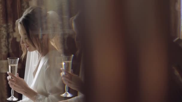 Beautiful and lovely bride in night gown and veil sitting and drinking champagne — Stock Video