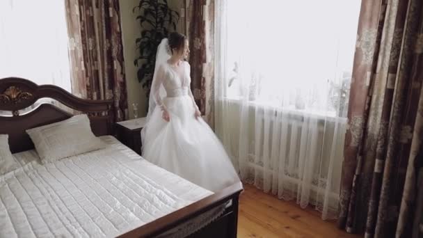 Krásná a krásná nevěsta na svatebních šatech u okna. Krásná žena — Stock video