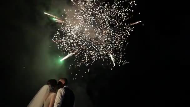Ζευγάρι στην αγάπη βλέποντας πυροτεχνήματα. Φιγούρα νεόνυμφοι σε φόντο πυροτεχνημάτων — Αρχείο Βίντεο