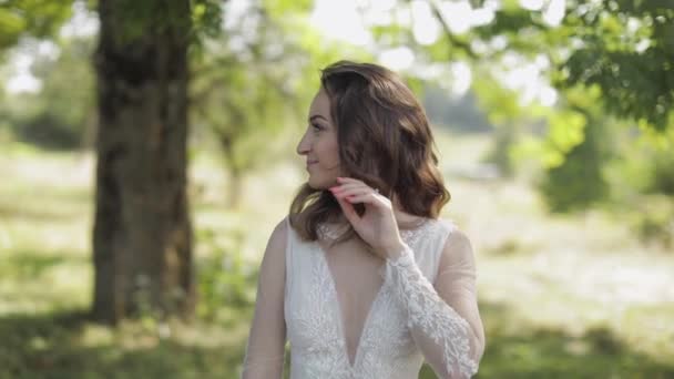 Hermosa y encantadora novia en vestido de novia en el parque. Movimiento lento — Vídeos de Stock